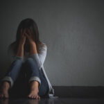 sad woman hug her knee and cry. Sad woman sitting alone in a empty room.